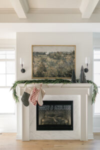 Stylish sconces from Franklin Lighting framing a fireplace, casting a warm glow over a festive mantel decorated for the holiday season.