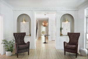 A foyer with a large gold chandelier and two gold sconces on either side from franklin lighting