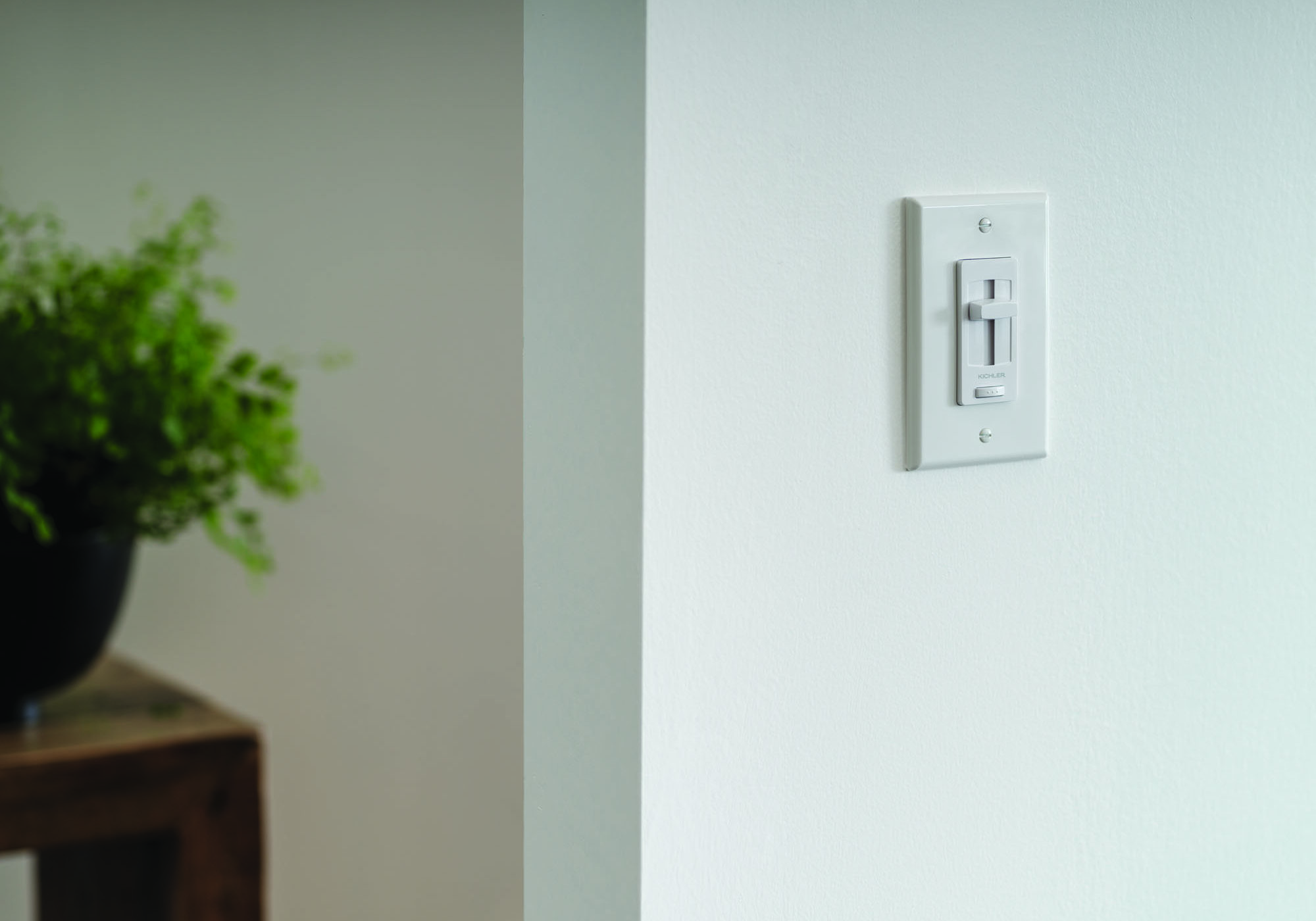 A close-up of a white wall with a digital dimmer switch or smart-home controller plate installed.