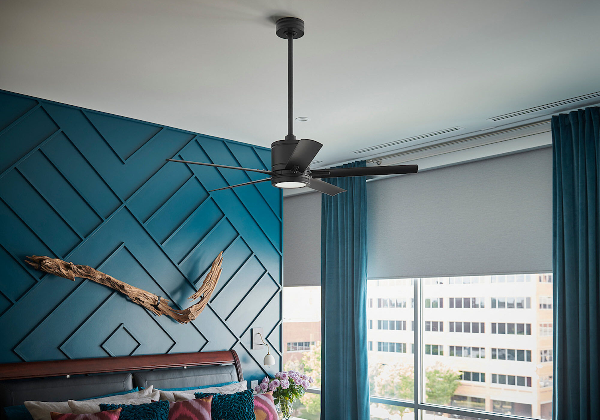 Industrial style ceiling fan with dark blades mounted against a blue geometric accent wall.
